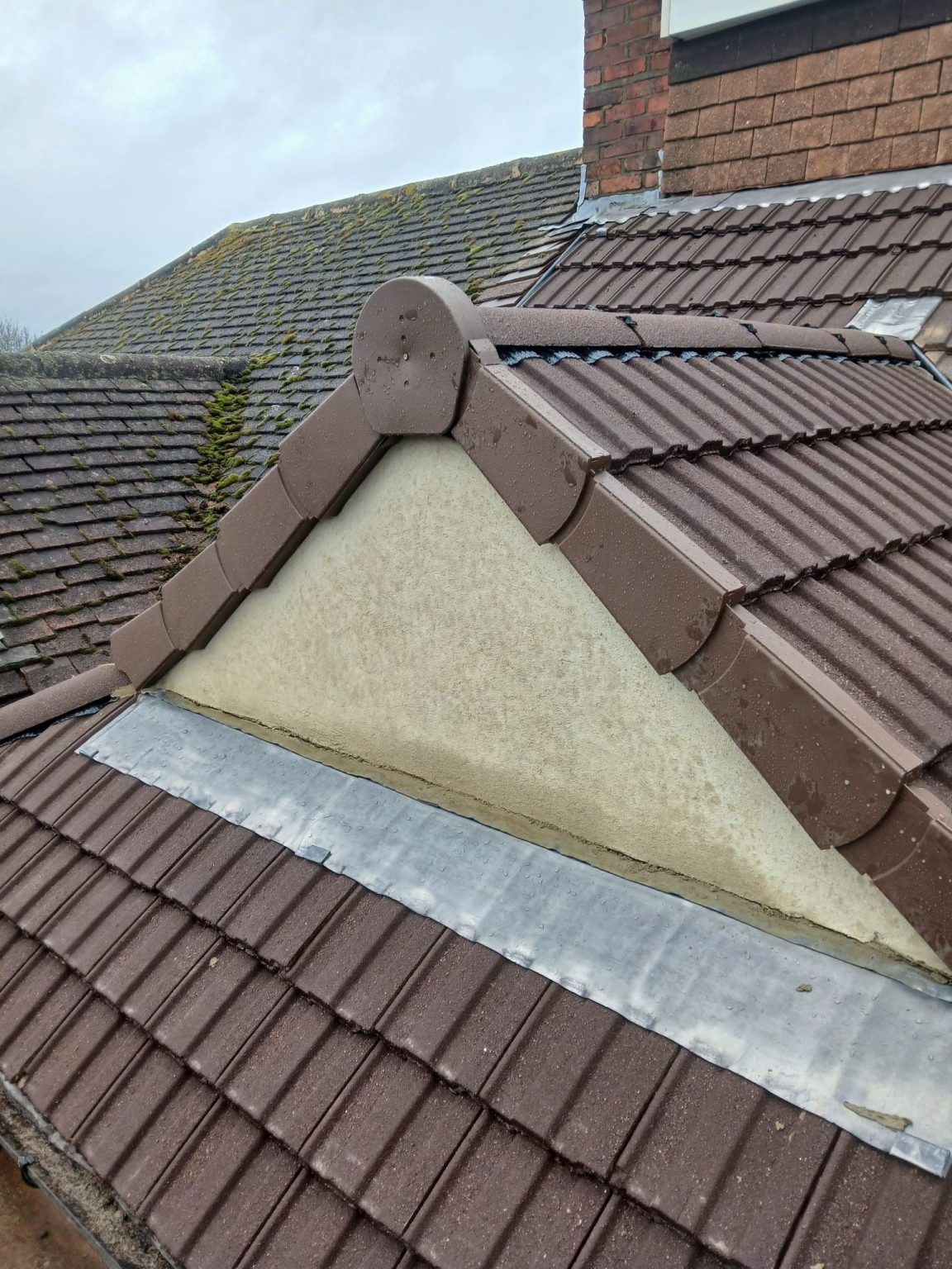 New brown roof tiles with ridge tiles, lead valley and rendered gable